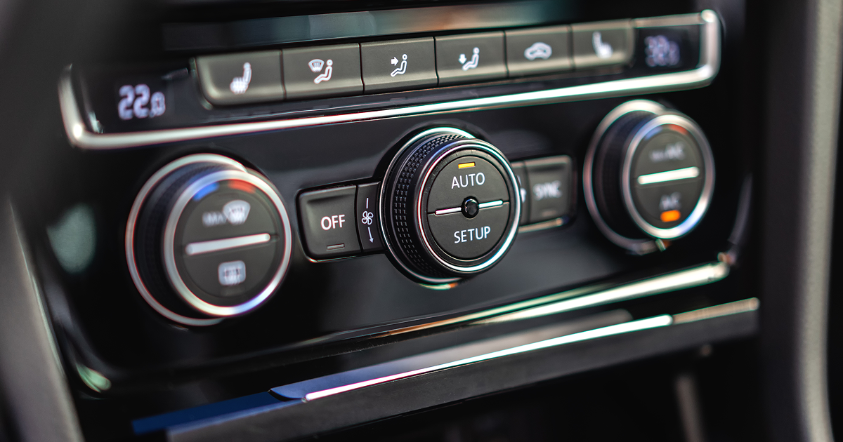 Car's climate control panel with knobs and buttons to adjust temperature and airflow.