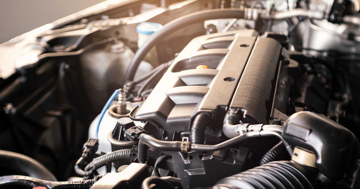 Car engine, close-up view. Black and gray components visible, including intake manifold and various tubes.
