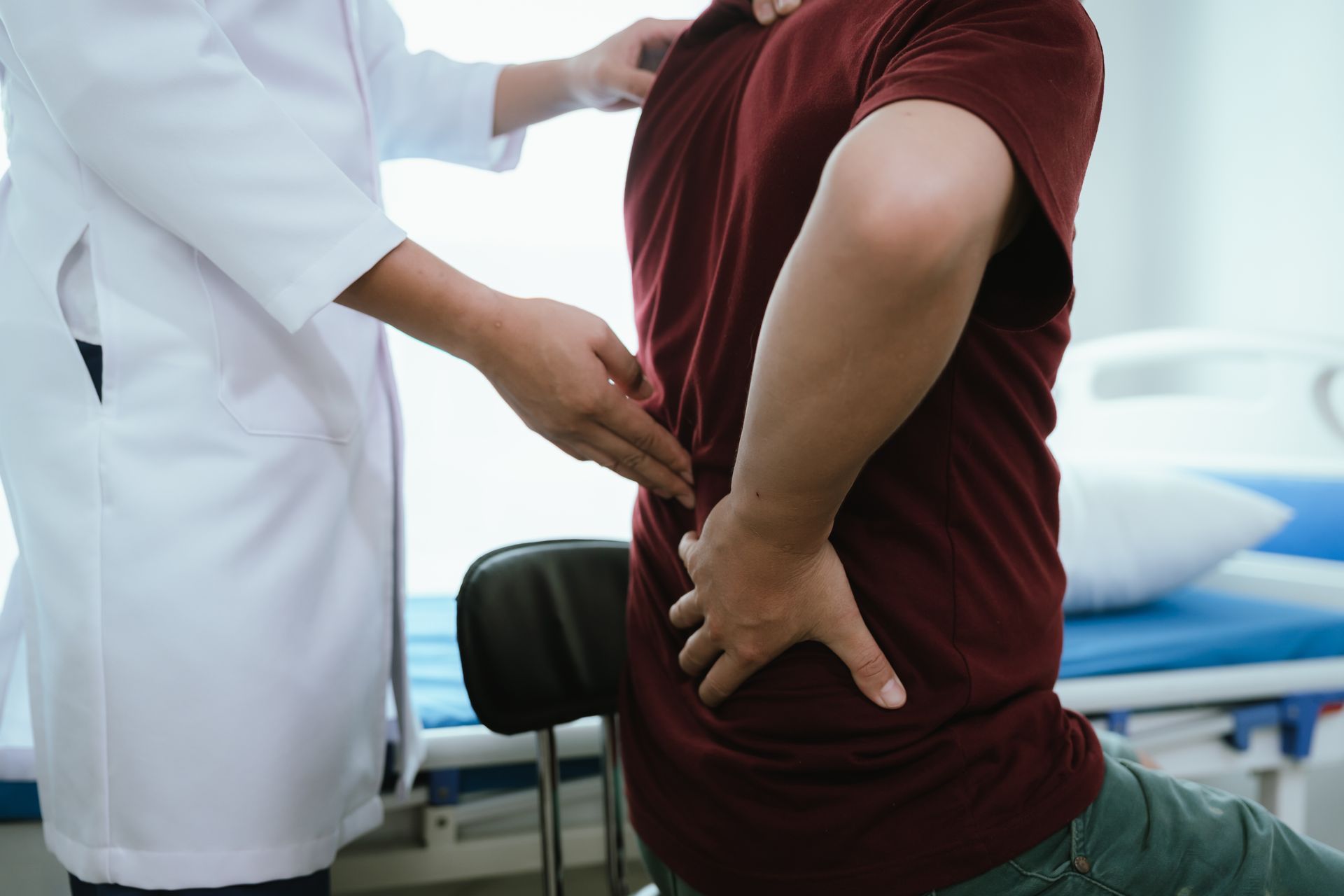 Doctor examining a patient's lower back in a clinic