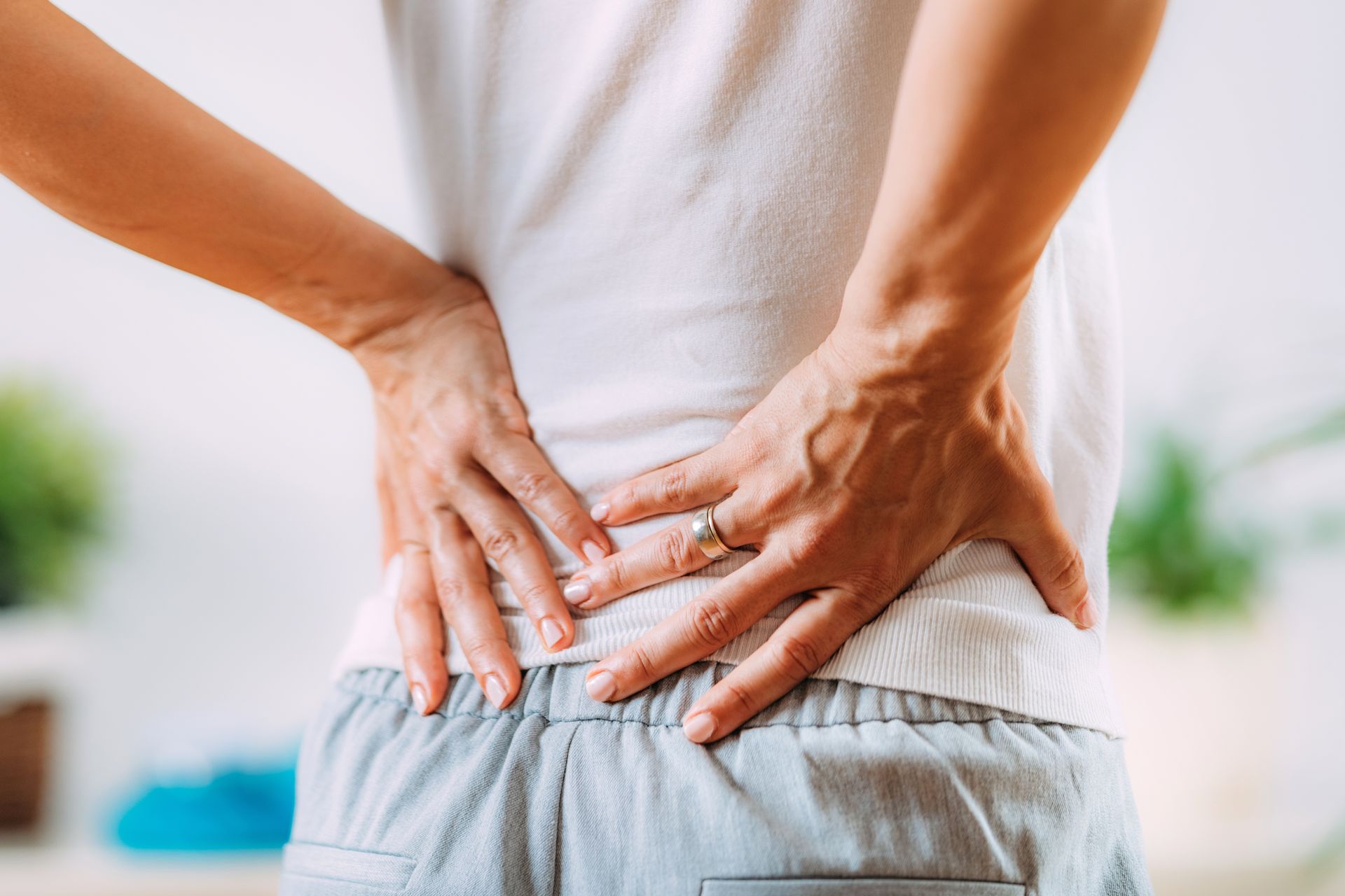 Hands pressing a lower back, indicating back pain or discomfort