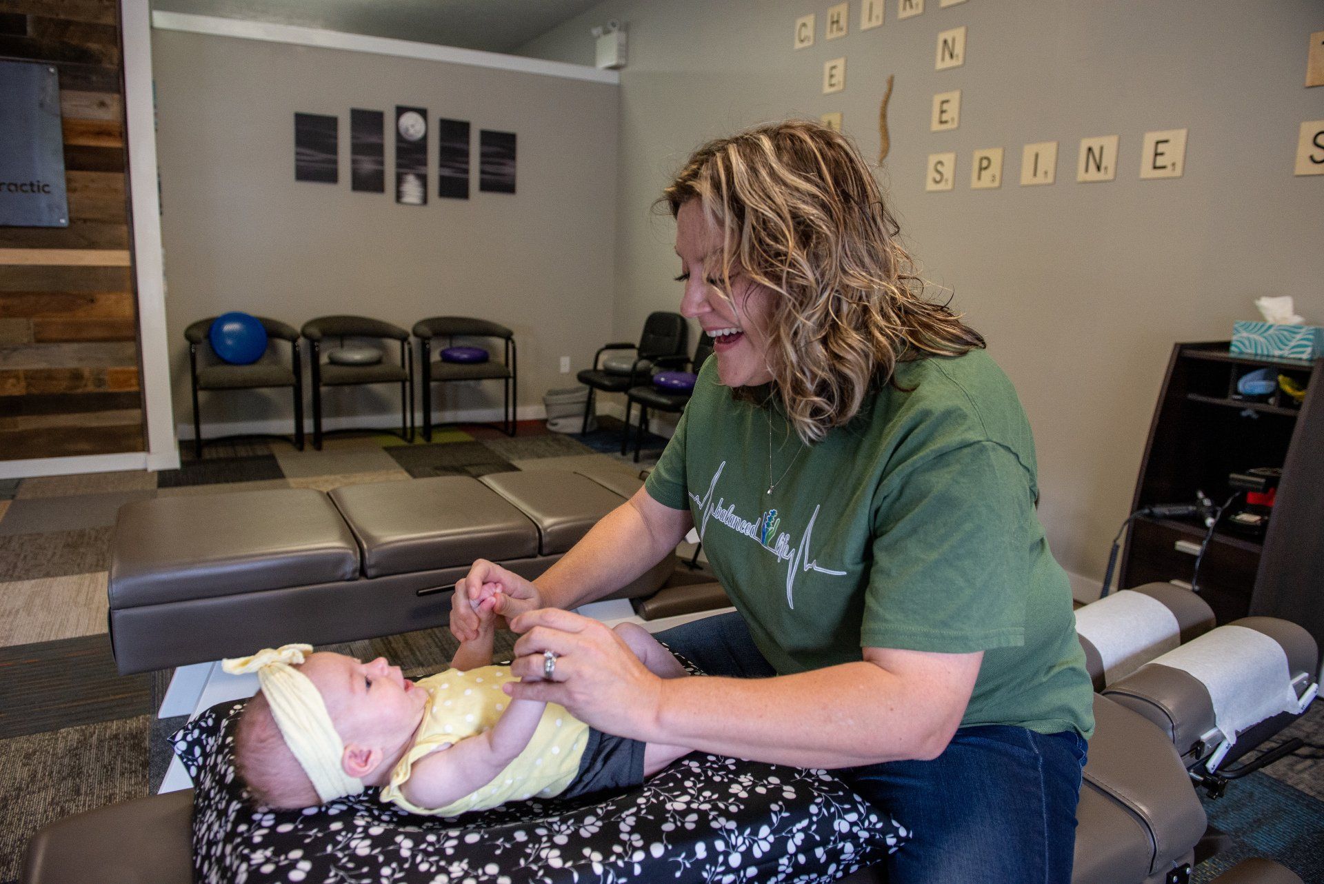 A woman is playing with a baby on a table in a room.