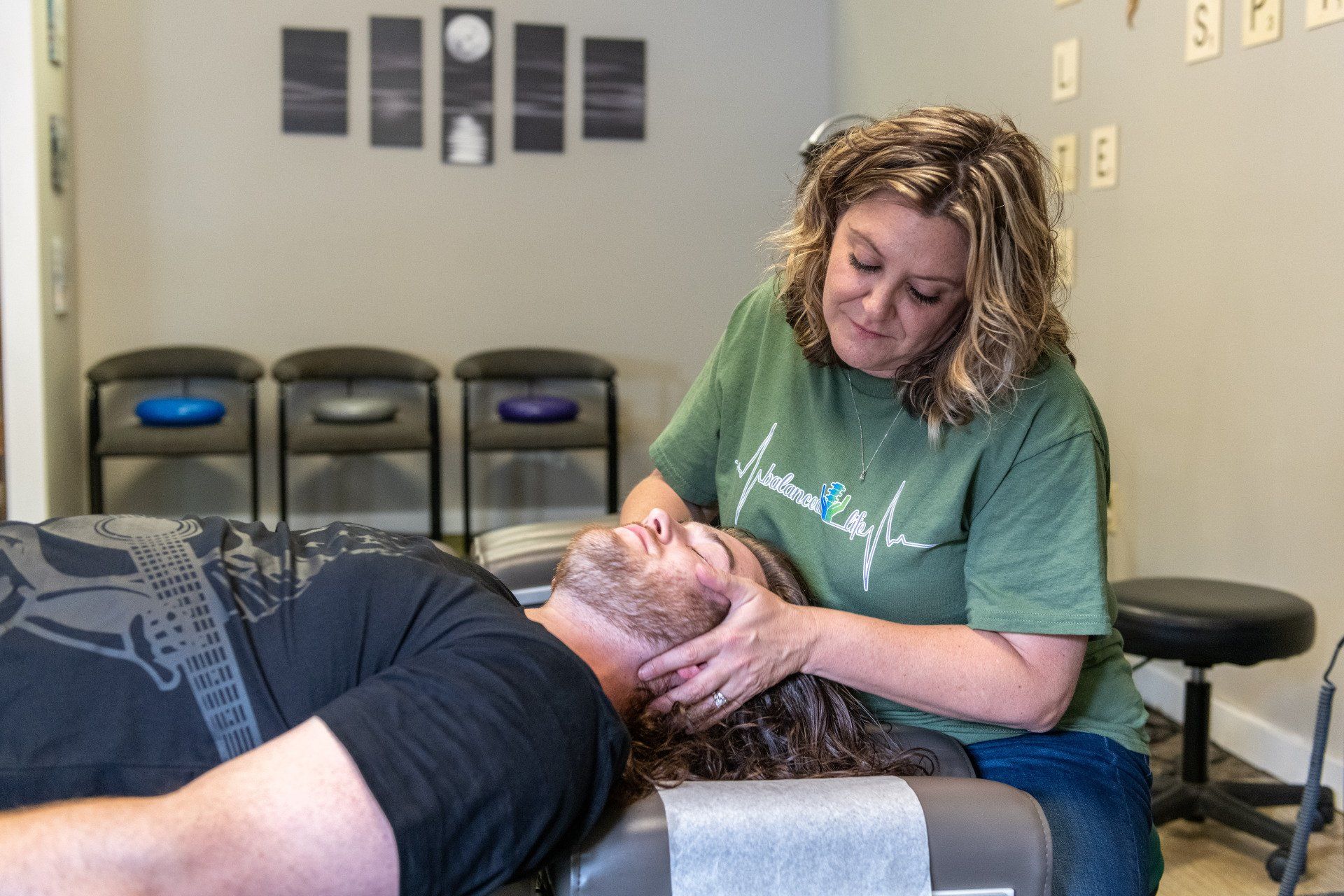 A woman is giving a man a head massage in a room.
