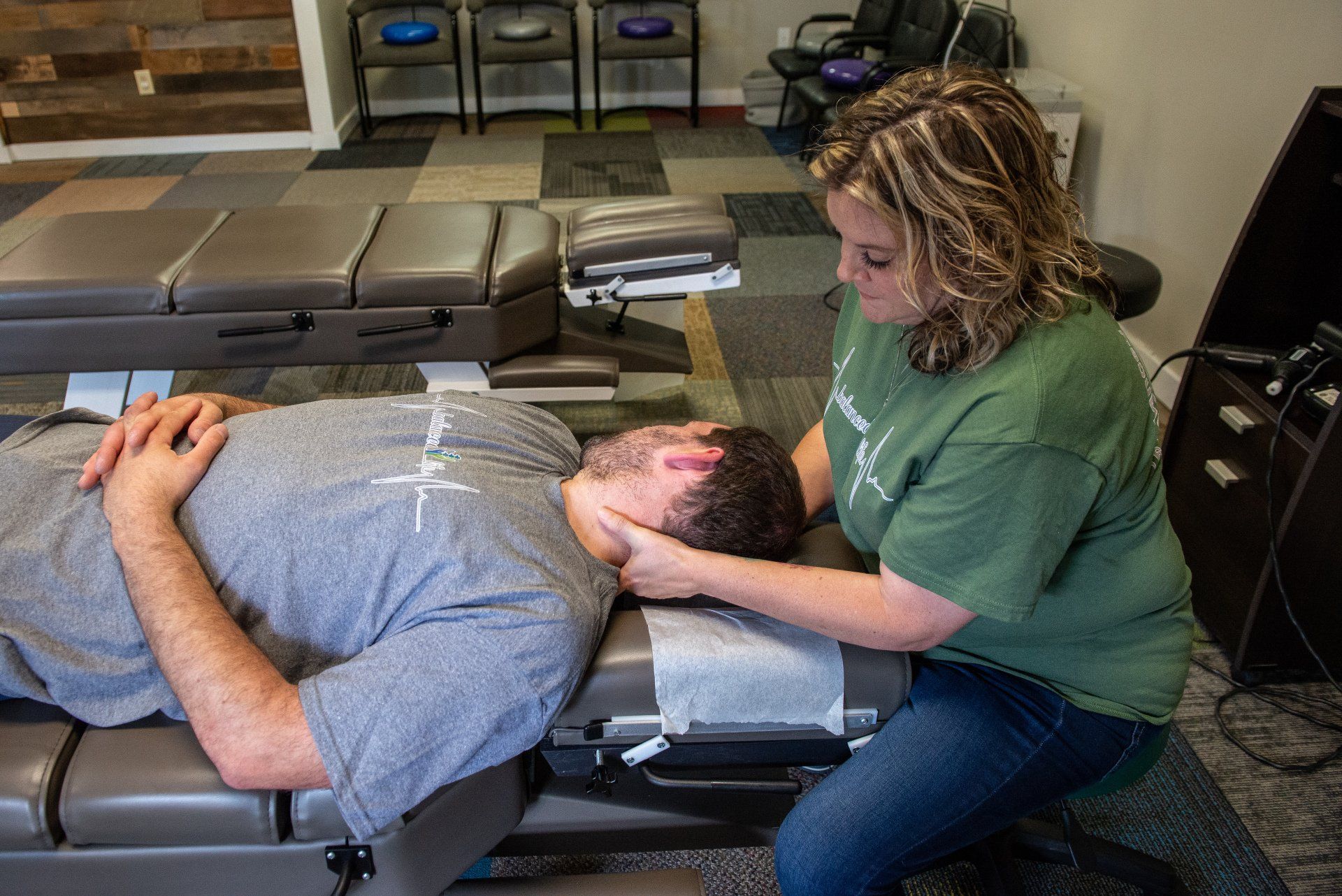A woman is giving a man a neck massage on a table.