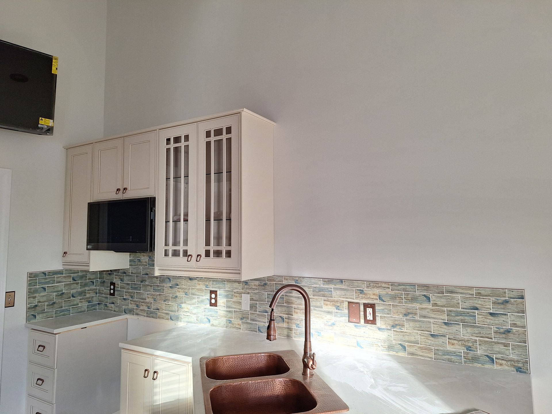 Bright kitchen with white cabinets, blue tile backsplash, and a copper faucet over a sink