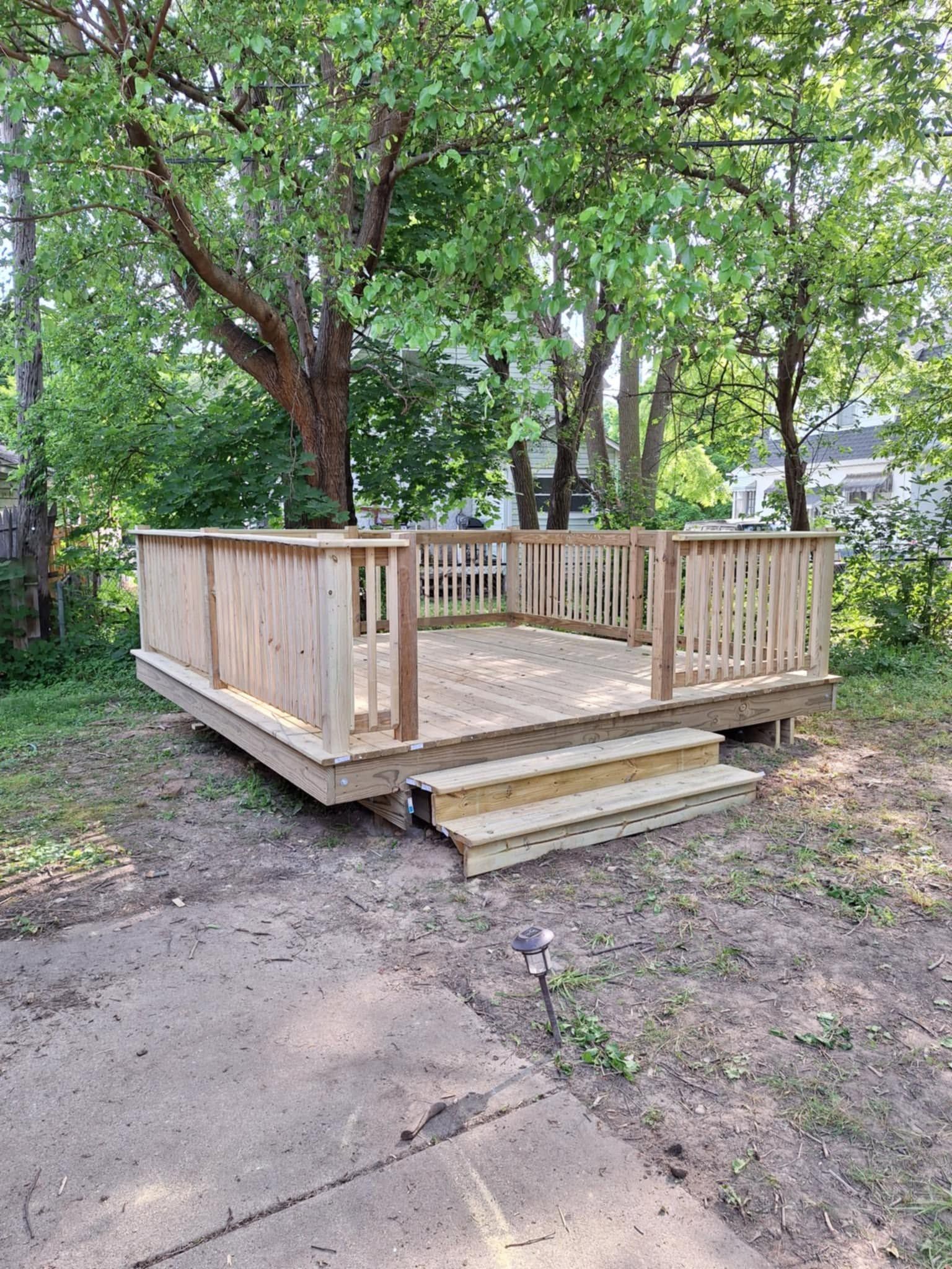 Wooden deck with railing and steps in a wooded yard