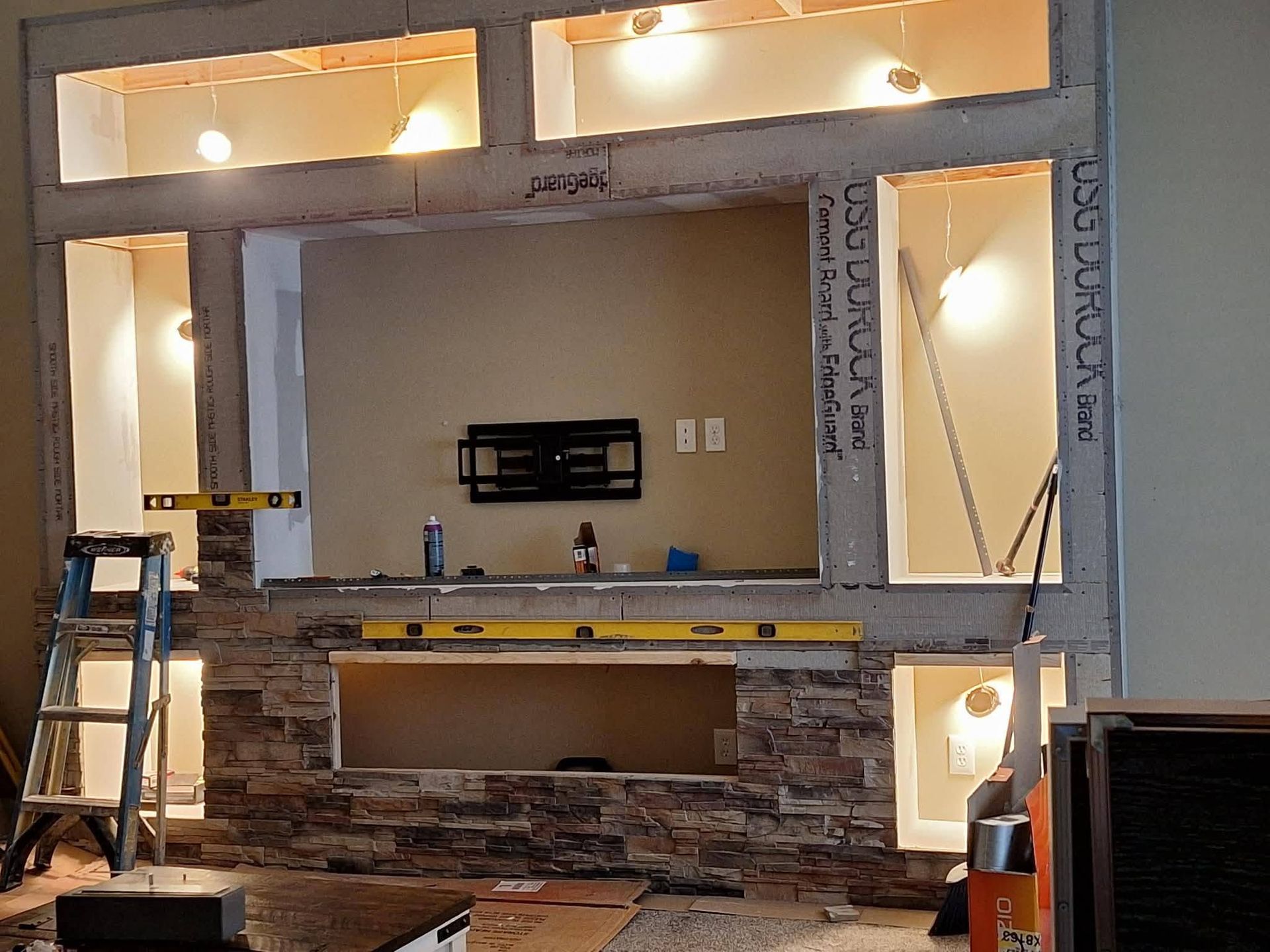 Partially finished kitchen with stone backsplash, open cabinets, and a ladder on the left.
