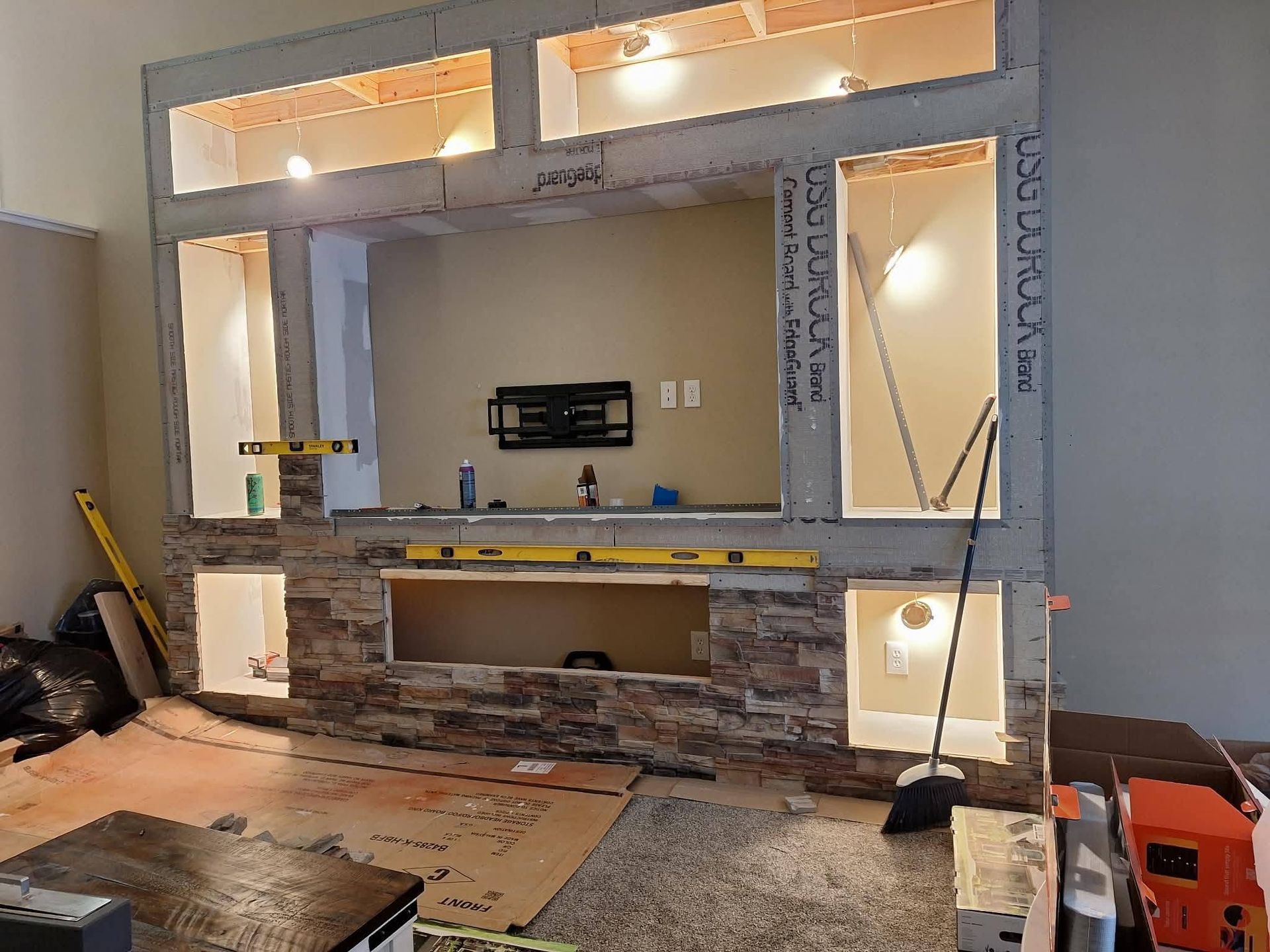 Living room under renovation with exposed wall framing and tools on the floor