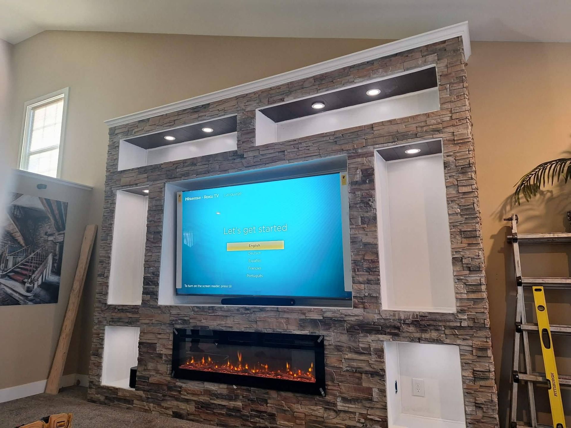 Living room wall with mounted TV, fireplace, stone surround, and recessed lights