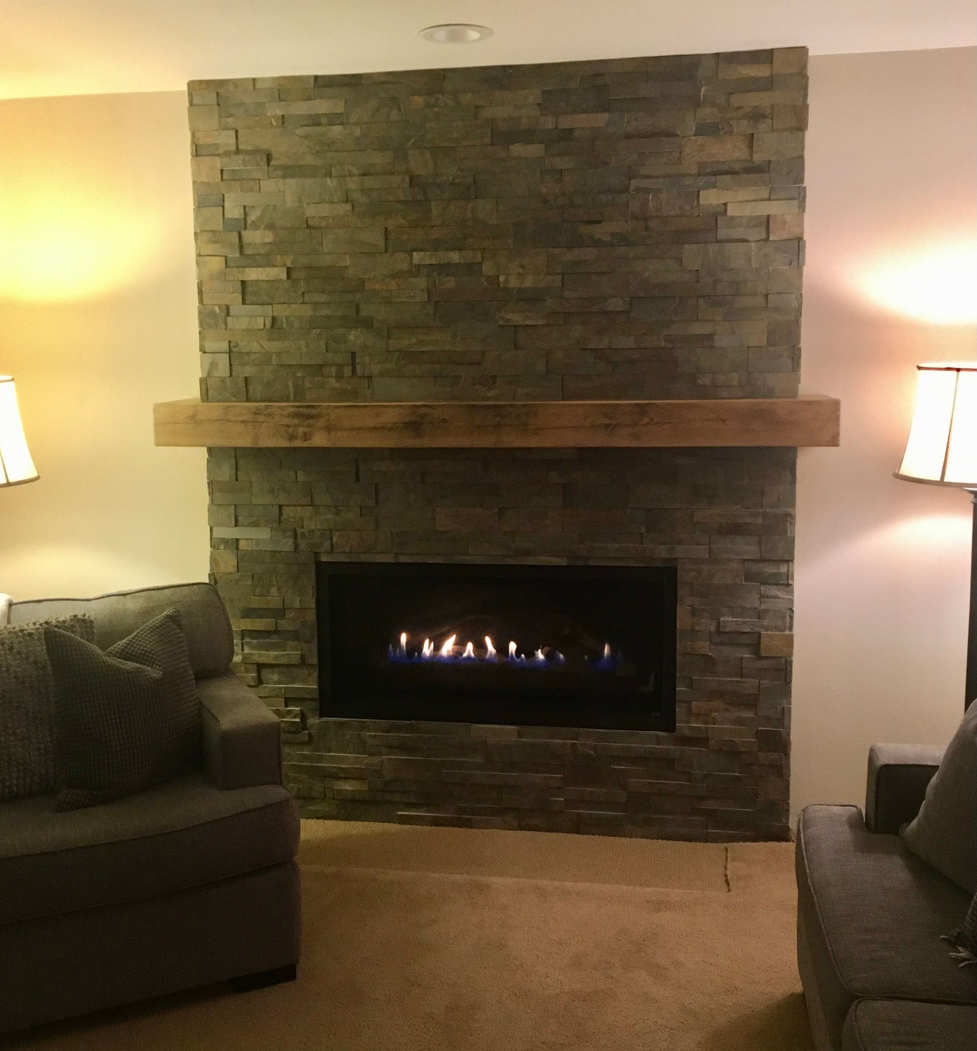 Living room with stone fireplace, lit gas fire, and sofas on both sides