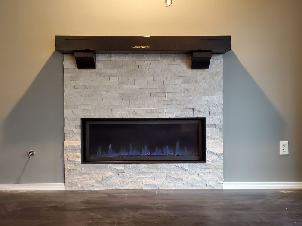 Modern living room fireplace with a white stone surround, dark mantel, and blue flames.