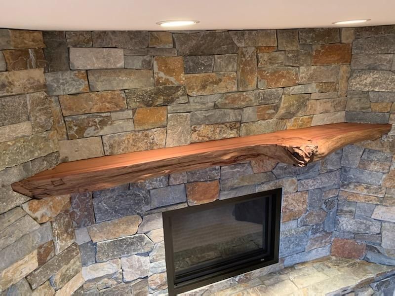 Stone fireplace with a rustic wooden mantel and recessed wall lights