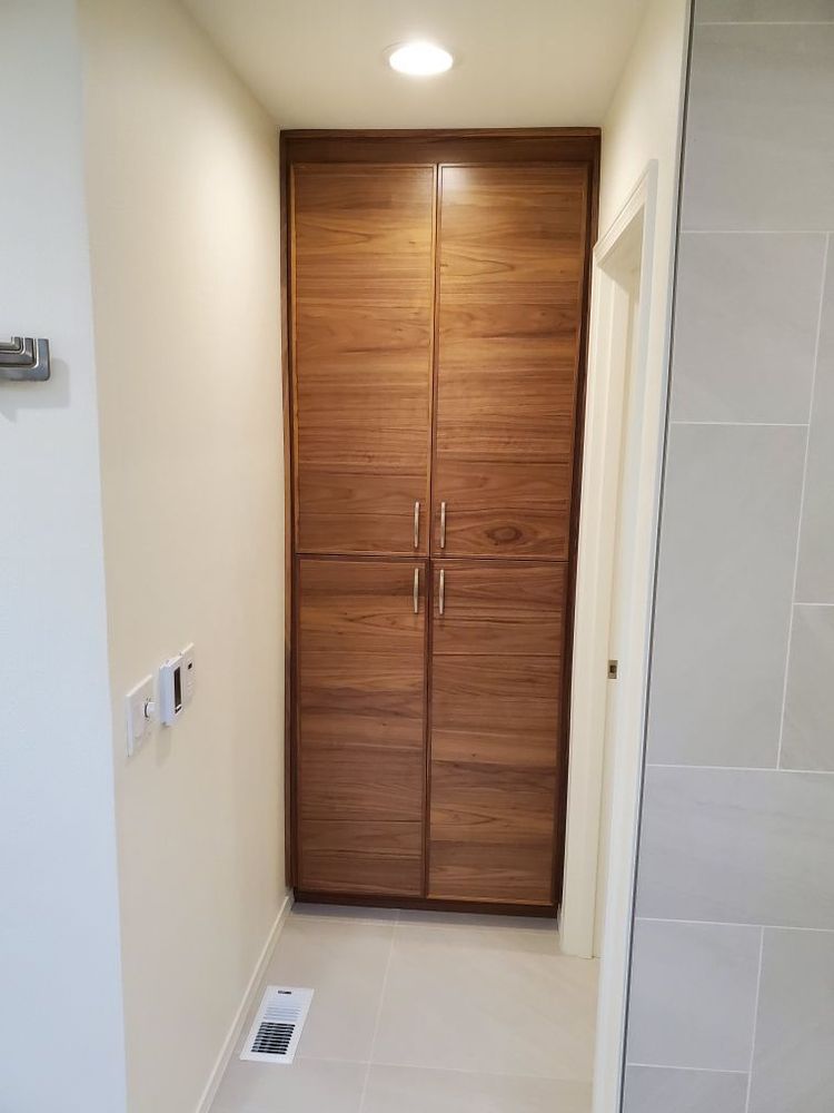 Narrow hallway with wooden double closet doors, white walls, and a floor vent on the left.