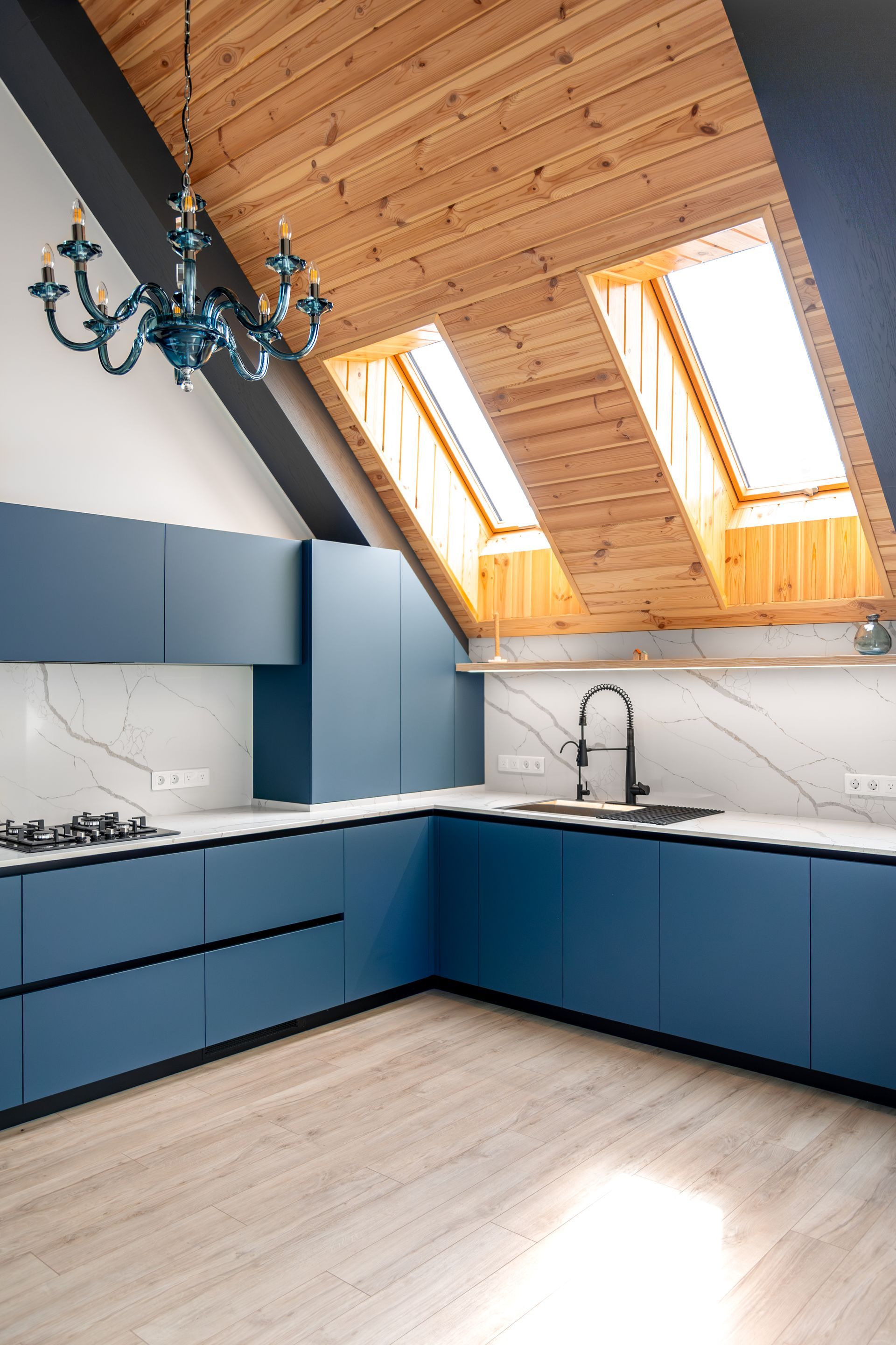 Modern kitchen with blue cabinets, skylights, wood ceiling, and marble backsplash