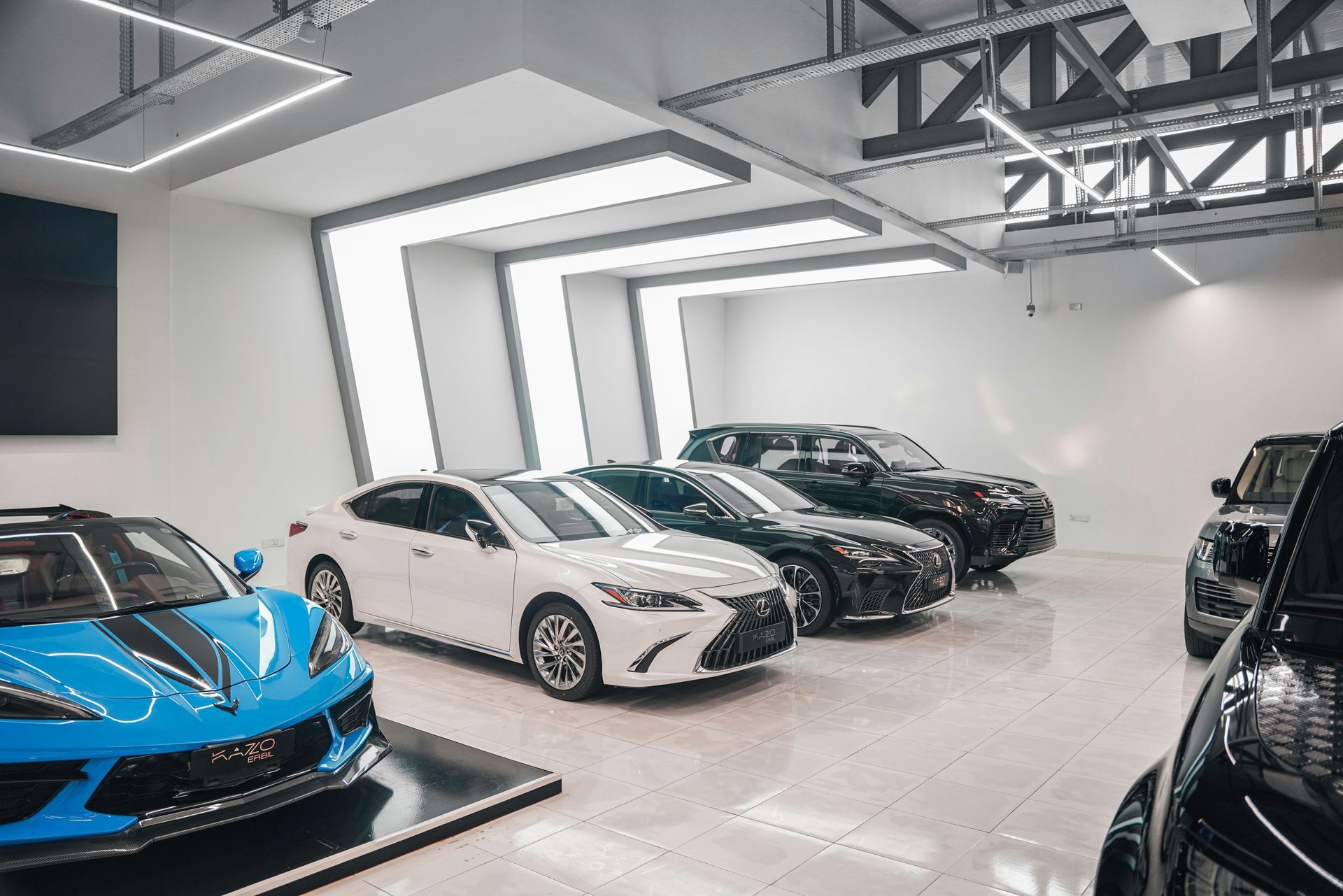 Luxury sports cars lined up in a bright showroom, including blue, white, and black vehicles.