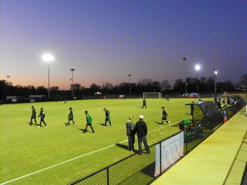 A group of people are playing soccer on a field at night