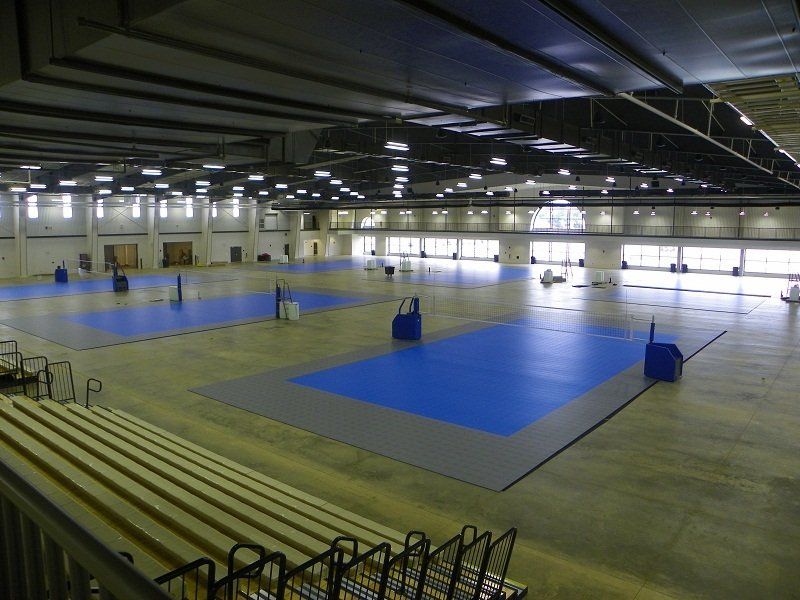 A large indoor gym with blue floors and bleachers