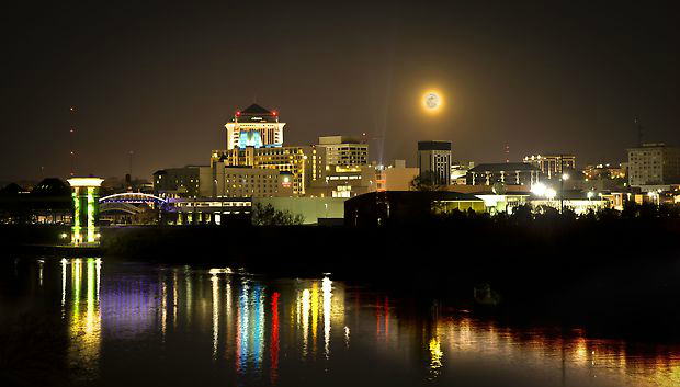 A city at night with a full moon in the sky