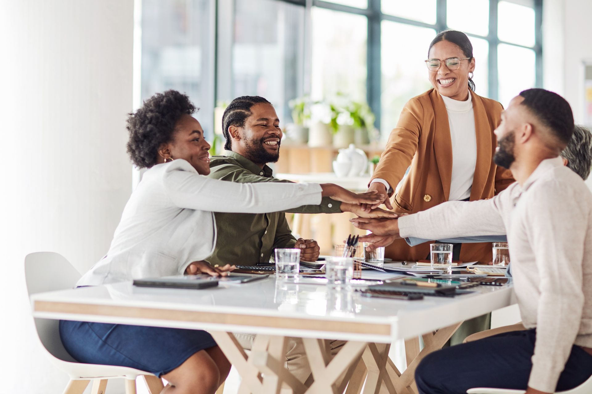 A group of business people are giving each other a high five in an office.
