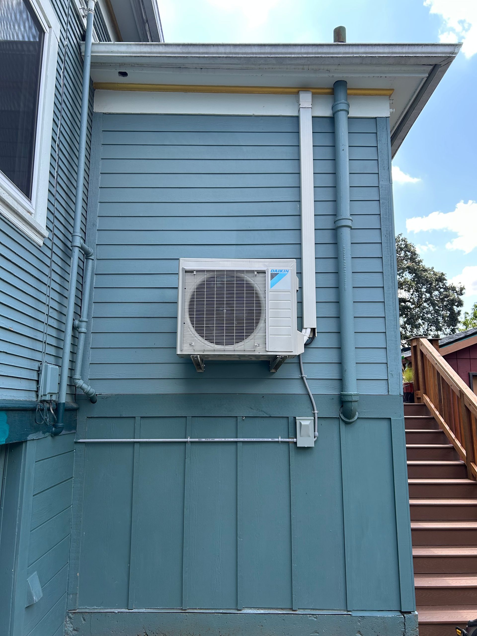 Blue house exterior with wall-mounted air conditioner and staircase on the right