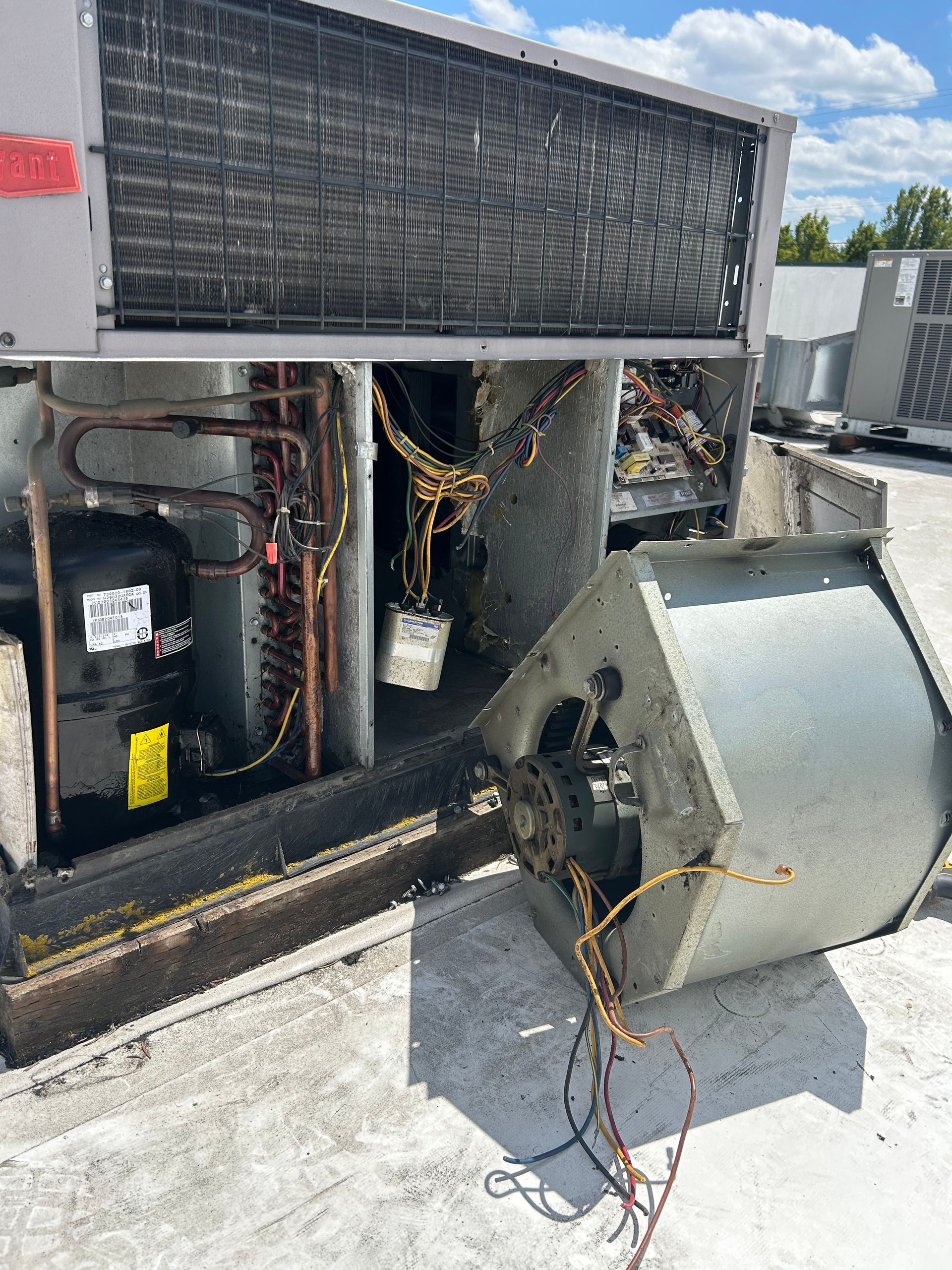 Broken rooftop HVAC unit with detached fan housing and exposed wiring on a flat roof