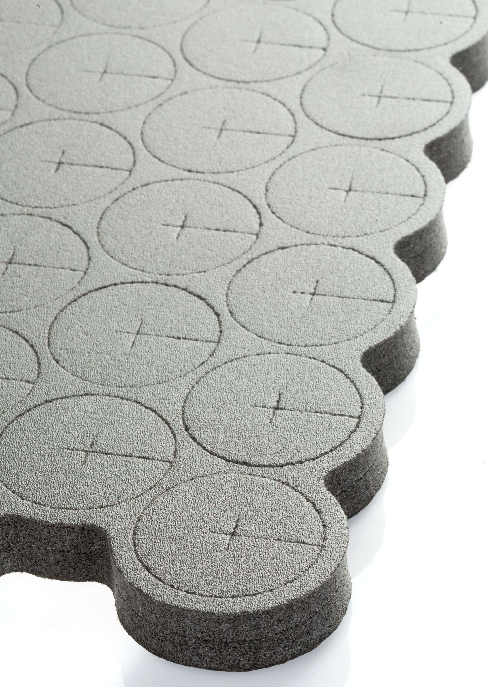 Gray foam puzzle mats with circular patterns on the surface, stacked in an interlocking edge pattern