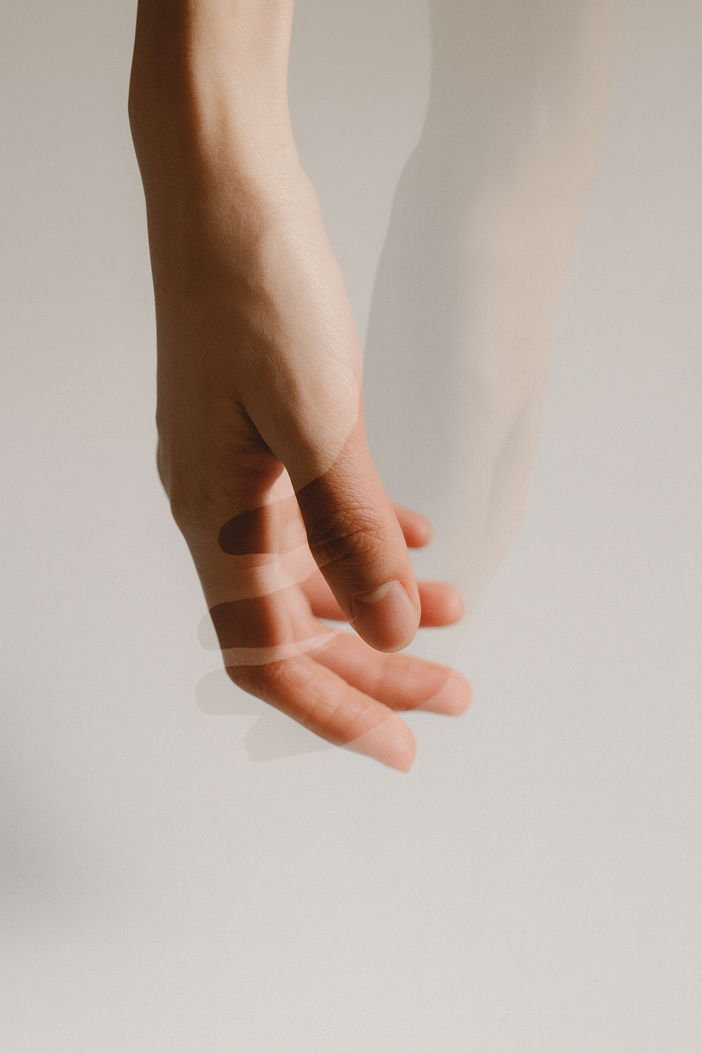Mano, movimento sfocato, protesa verso il basso. Pelle chiara, sfondo bianco.