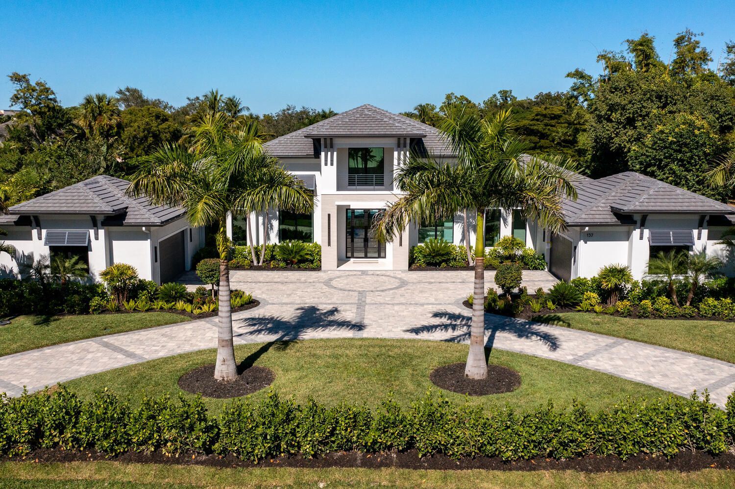 A large white house with two palm trees in front of it.