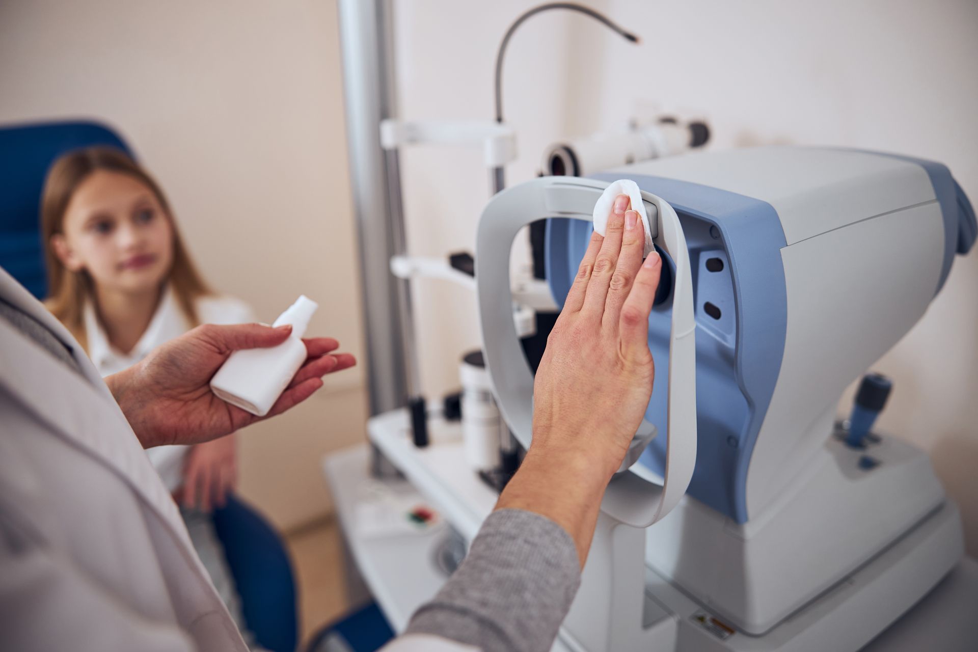 Side view portrait of doctor arms cleaning modern device with antibacterial spray before the examining eyesight of patient in ophthalmology clinic