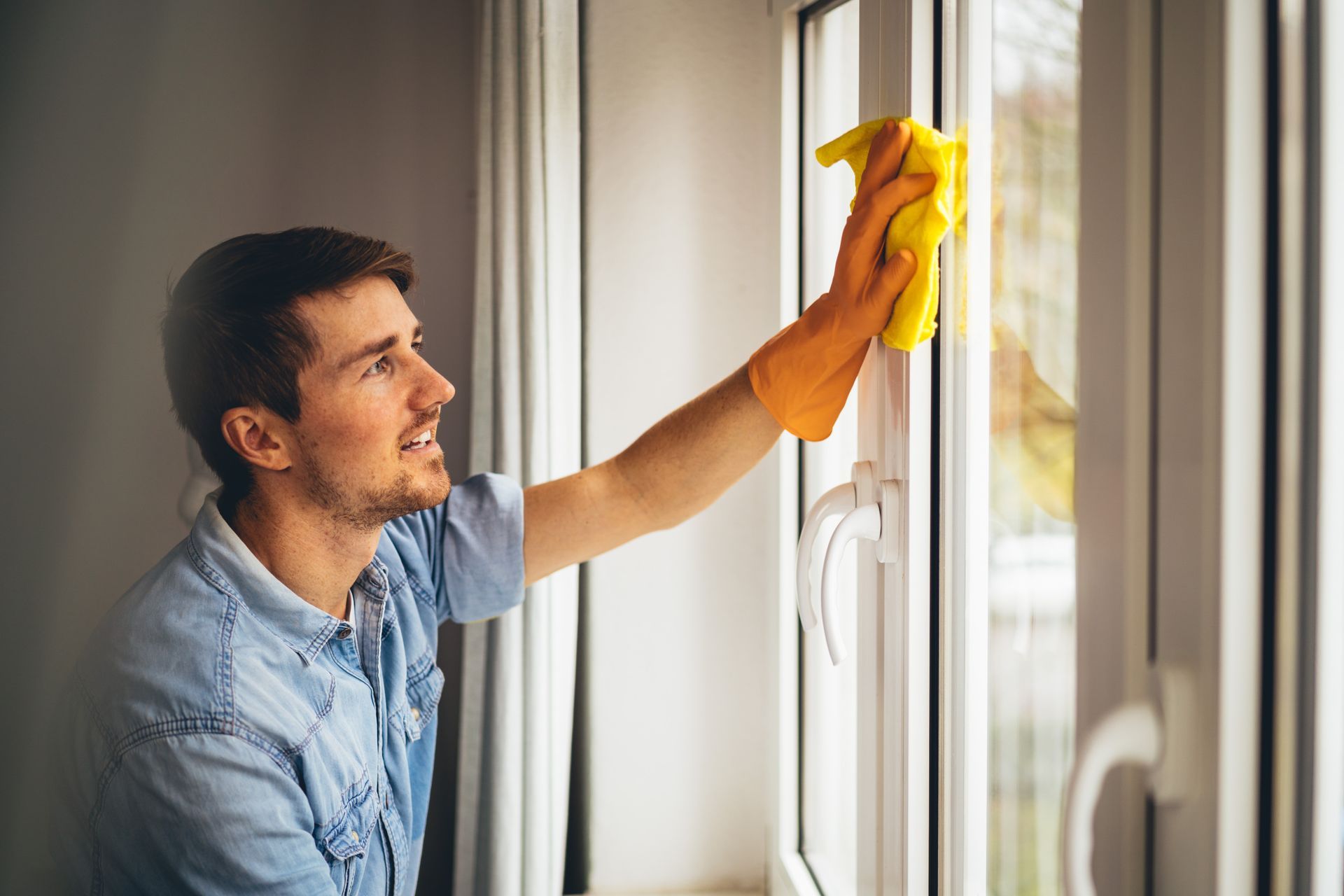 young man cleaning windows in the house