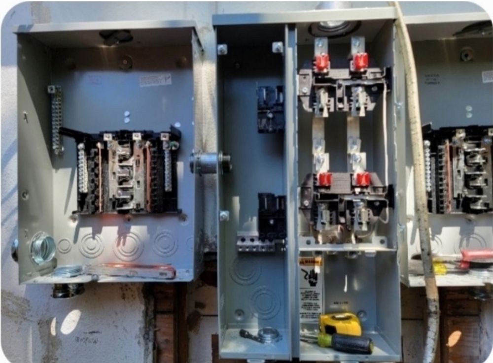 Open electrical meter boxes with exposed wiring and components, outdoors.