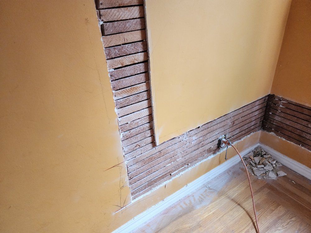 Interior wall with section of drywall removed, revealing wood lath framework, and a corner section of the wall.