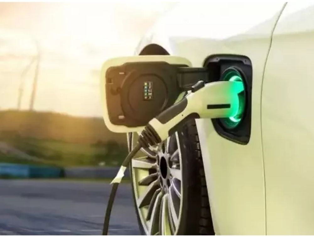 White electric car charging, green light illuminating charging port.