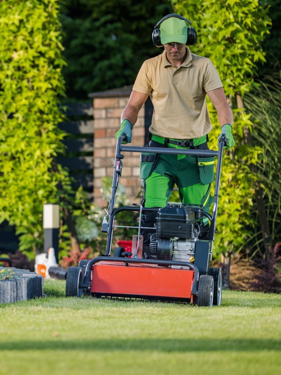 A man is mowing a lush green lawn with a lawn mower.