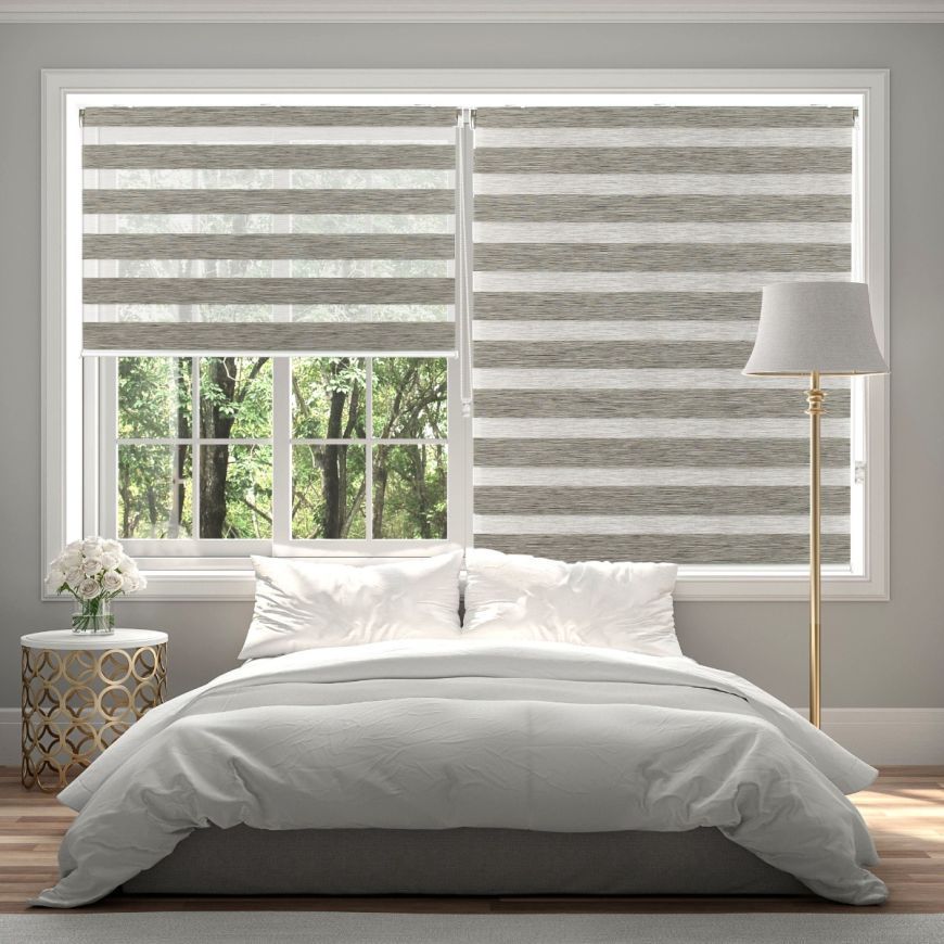 A bedroom with a bed , lamp , and window with striped blinds.