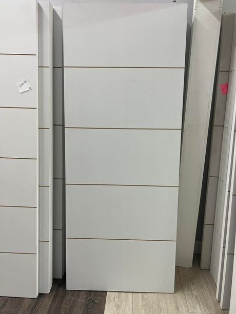 A stack of white doors sitting on top of each other in a room.