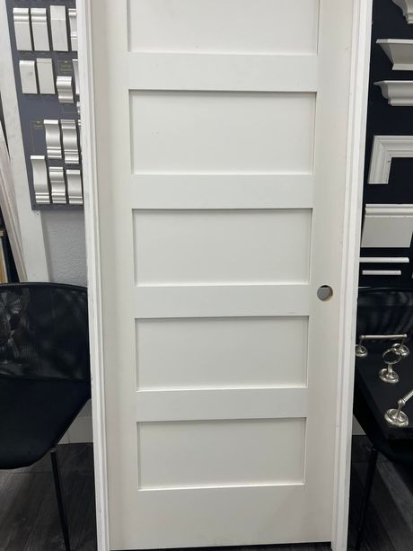 A white door with five panels is sitting in a room