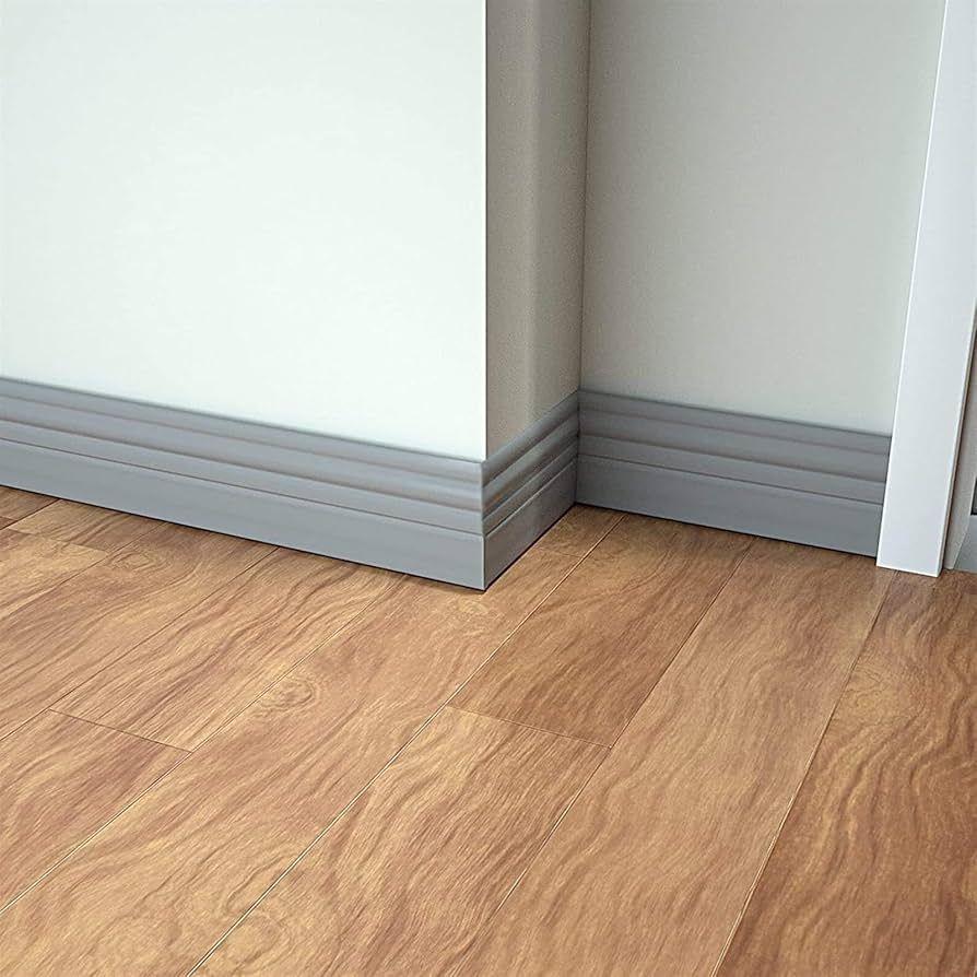 A corner of a room with a wooden floor and a white wall.