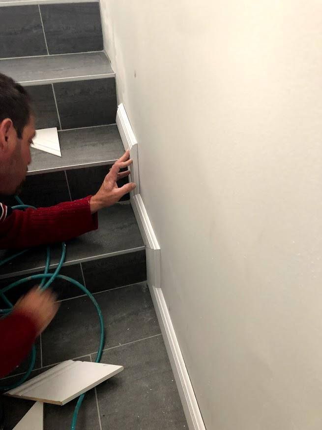 A man is working on a wall next to stairs.