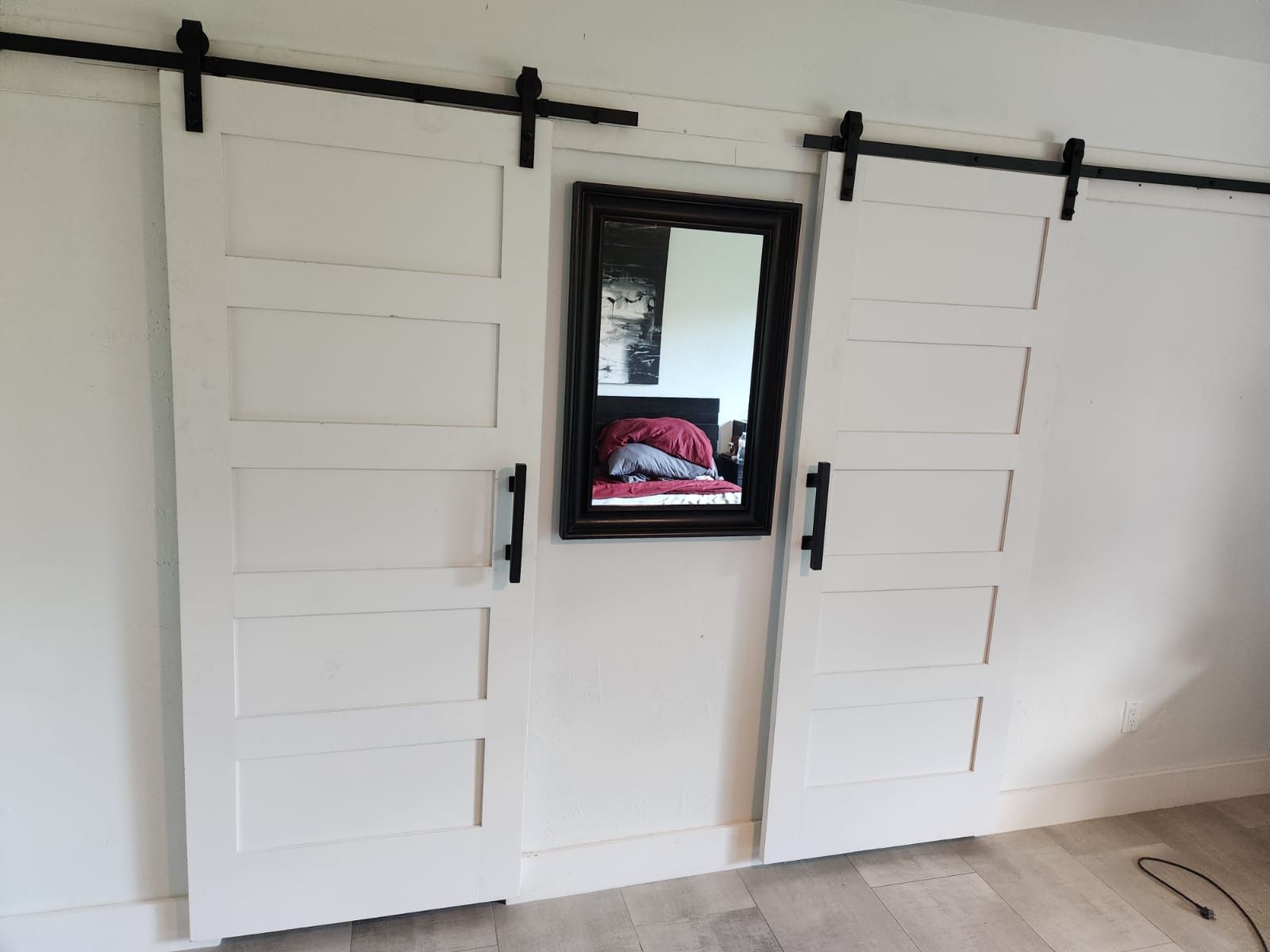 A bedroom with sliding barn doors and a mirror
