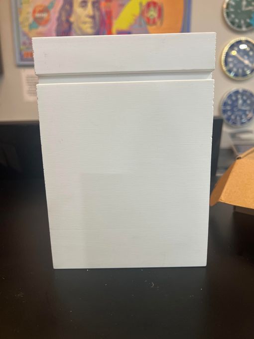 A white box is sitting on a table in front of a painting.