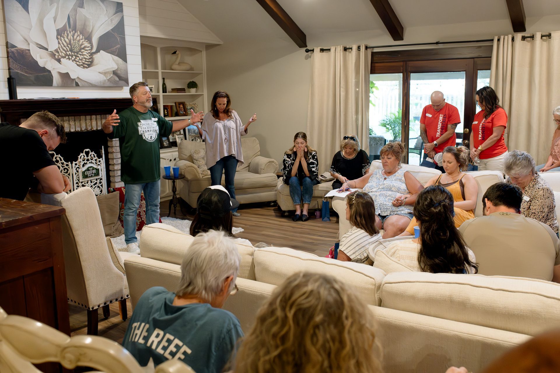 Group of people gathered in a living room in prayer.