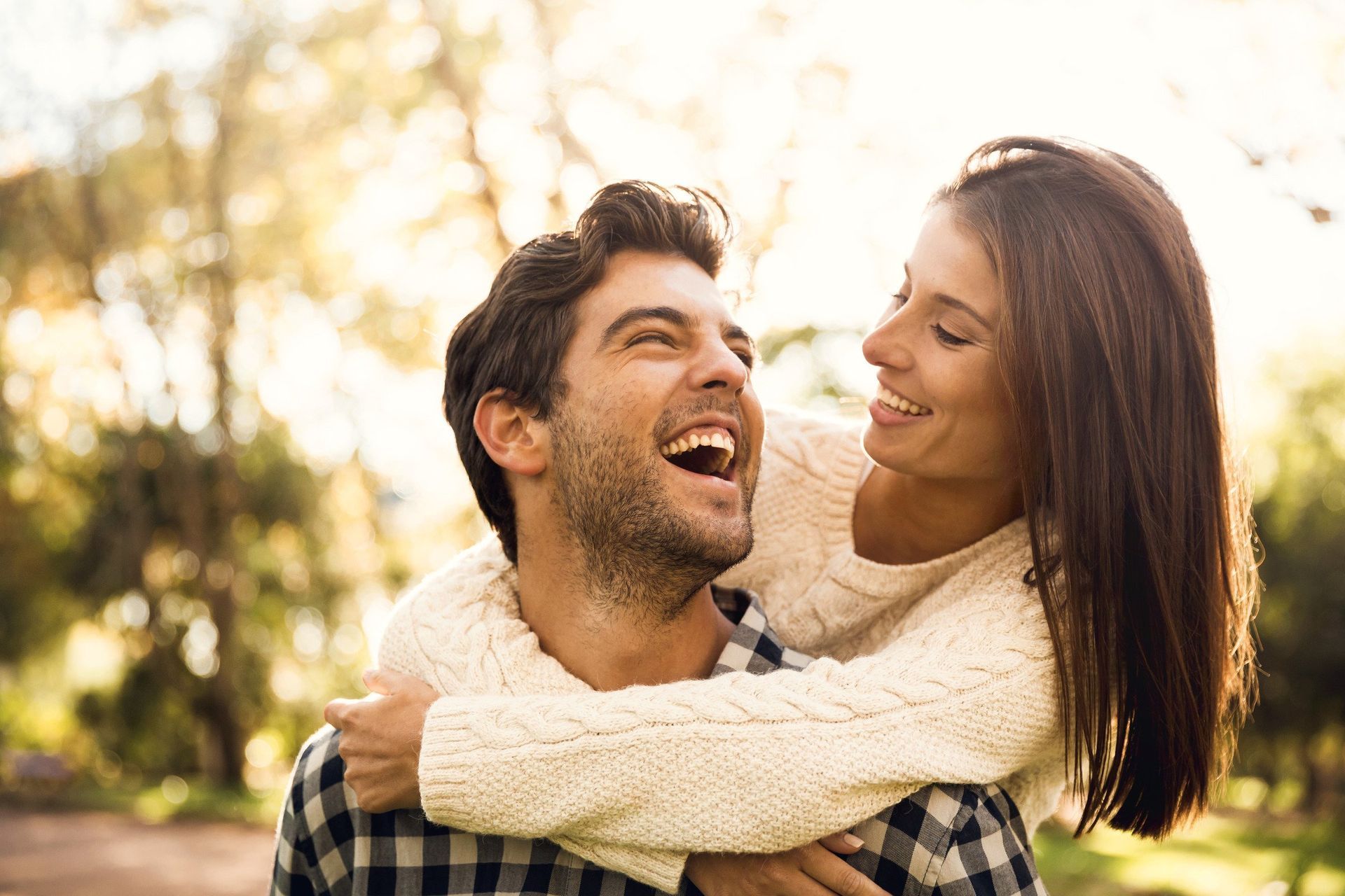 A man is carrying a woman on his back and they are laughing.