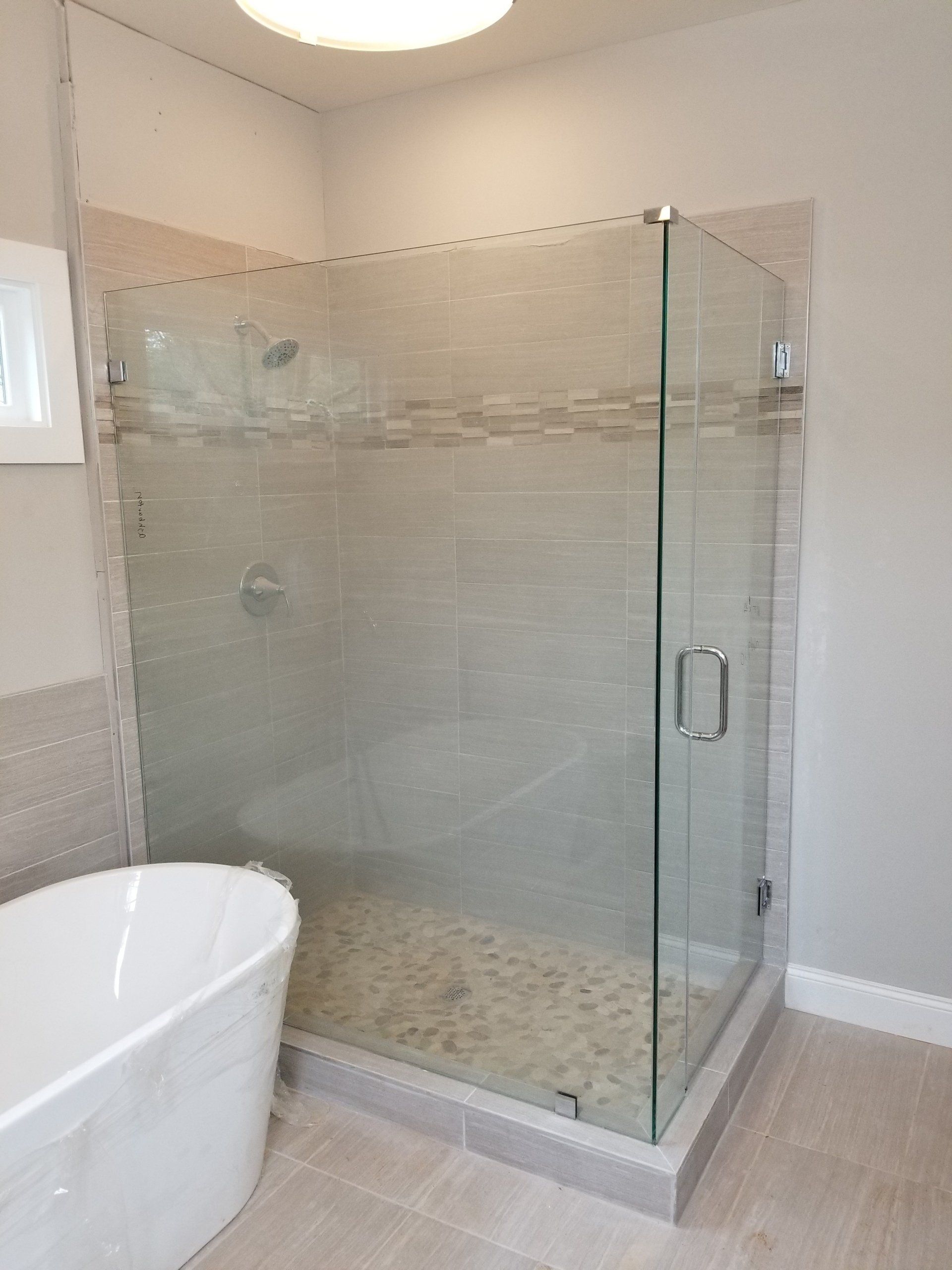 Modern bathroom with a glass shower enclosure and a freestanding white bathtub.