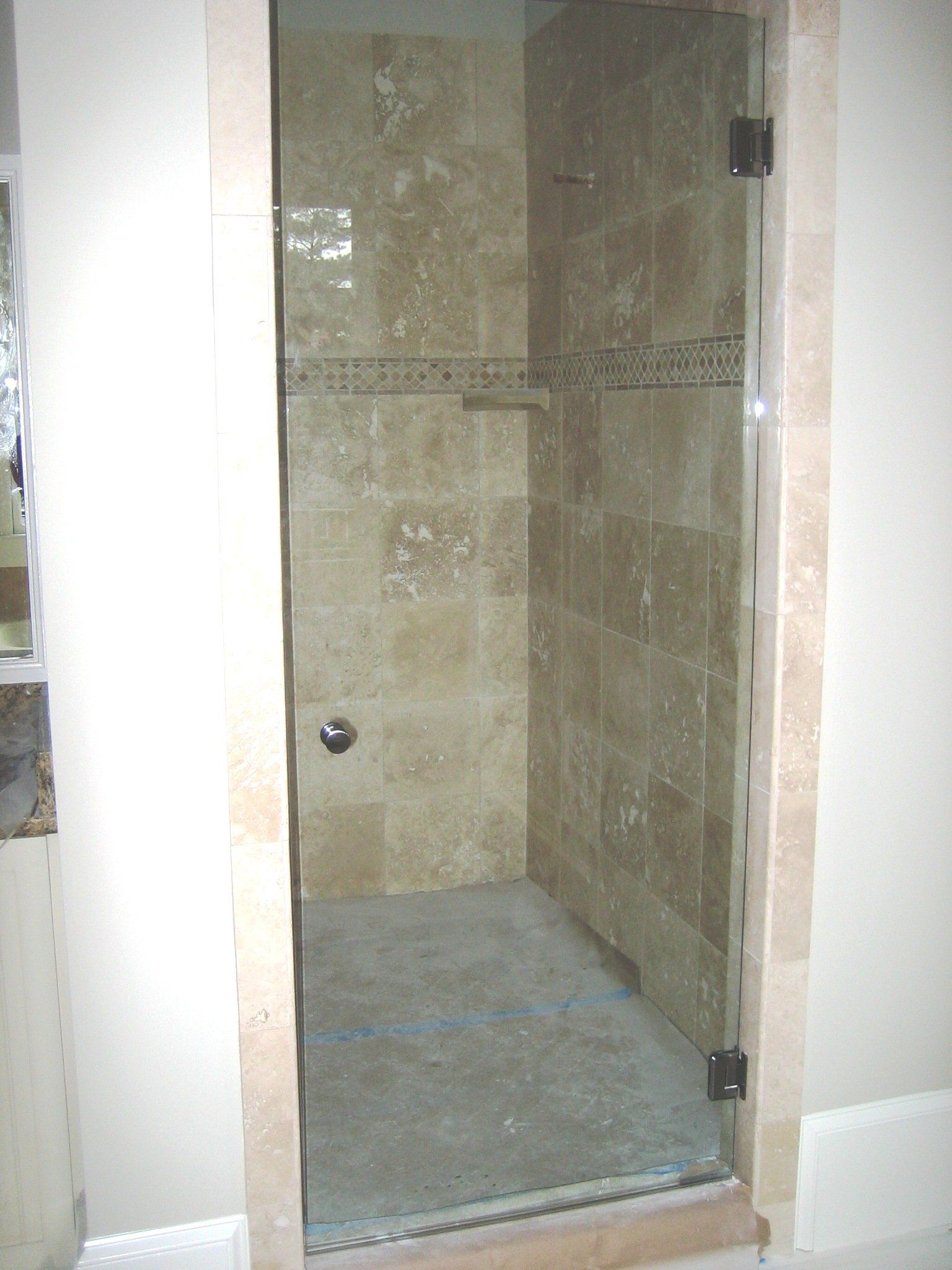 Shower stall with glass door and stone tile walls.