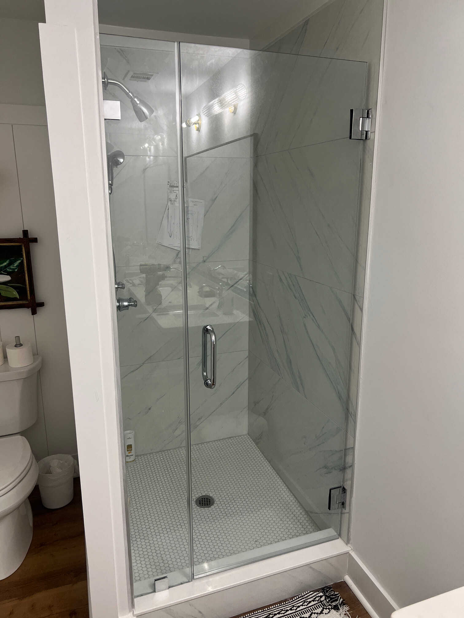 Shower with glass doors and white marble tile.