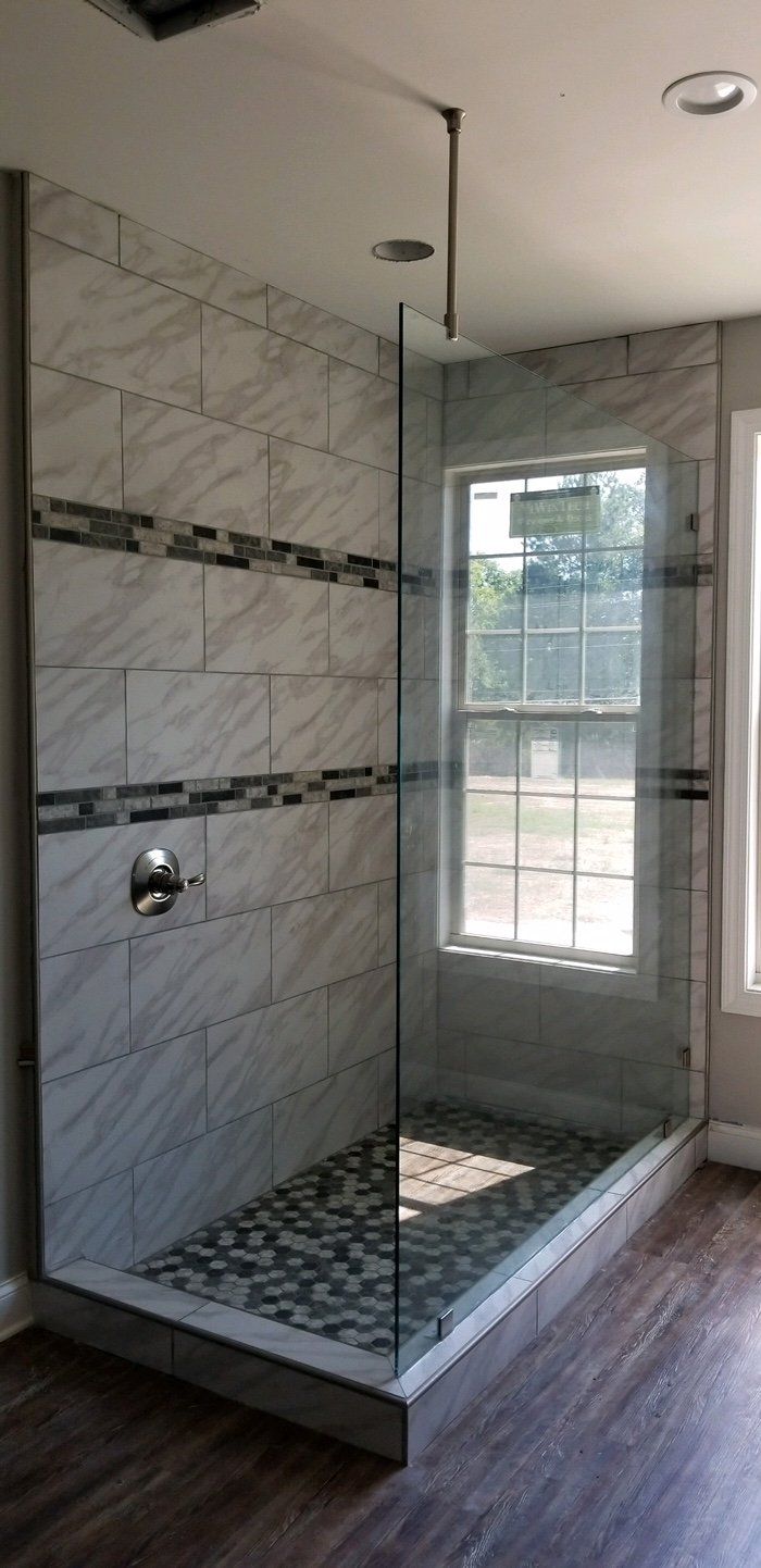 A modern shower with clear glass walls and pebble flooring. Gray tile lines the back wall.