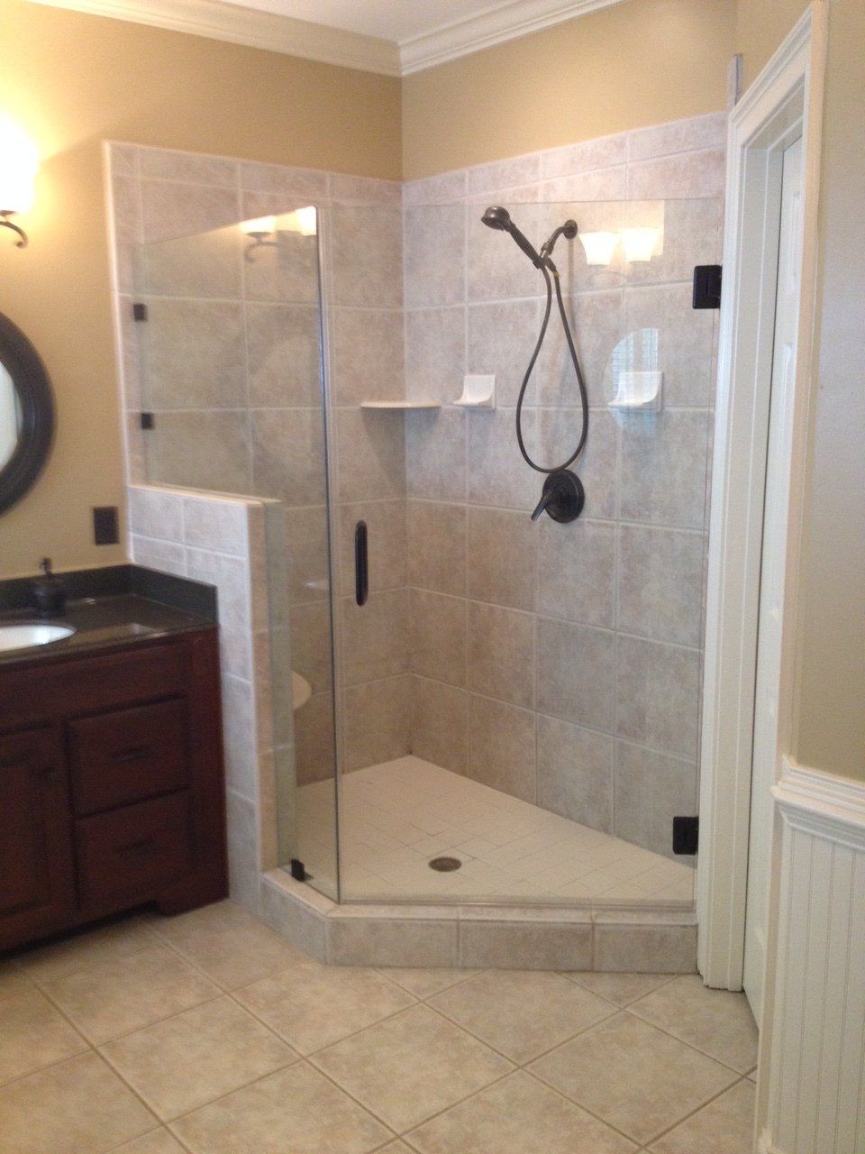 Bathroom with corner shower, beige tiles, dark brown vanity, and black shower fixtures.