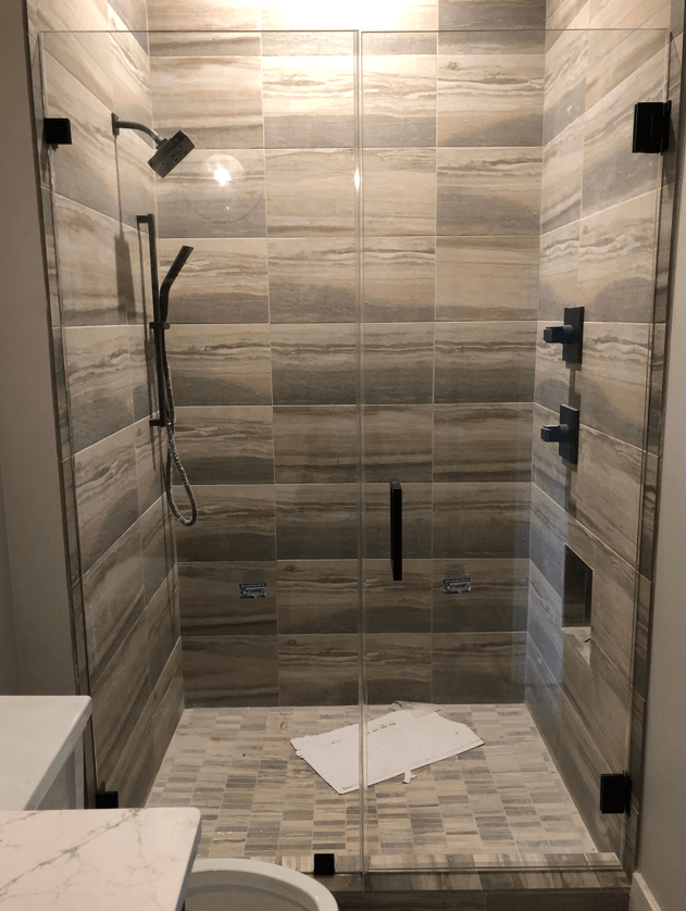 Glass shower with gray and white tile, black fixtures.