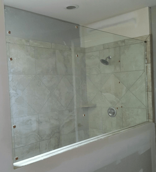 Glass shower enclosure with beige tiled walls.