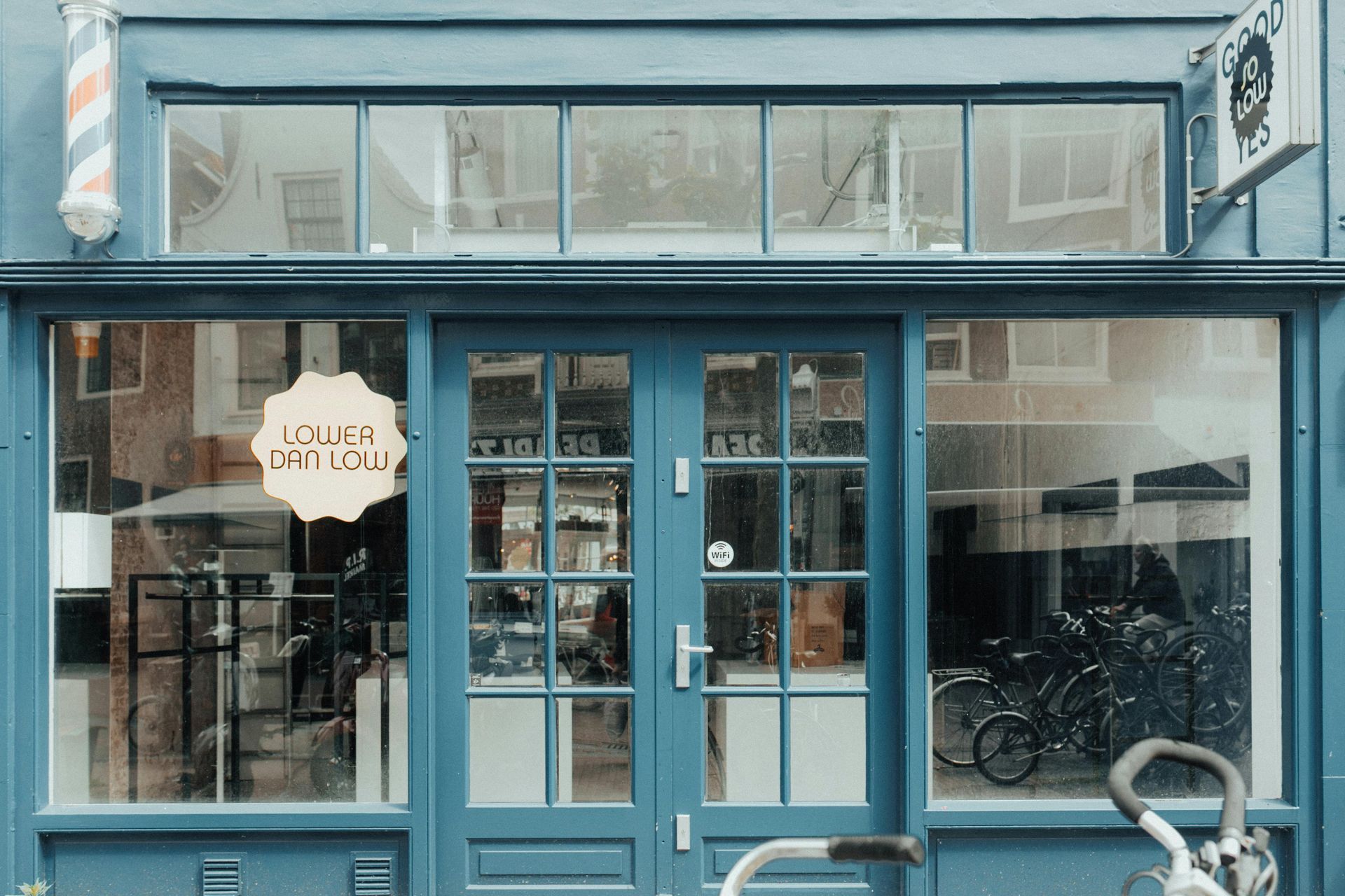 Blue storefront with glass windows and door, displaying a bicycle inside.